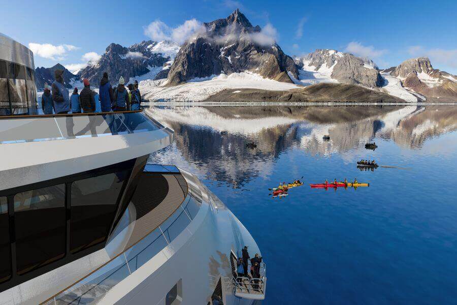 people looking out at snowy Antarctic mountains from the top observation deck of the Greg Mortimer ship